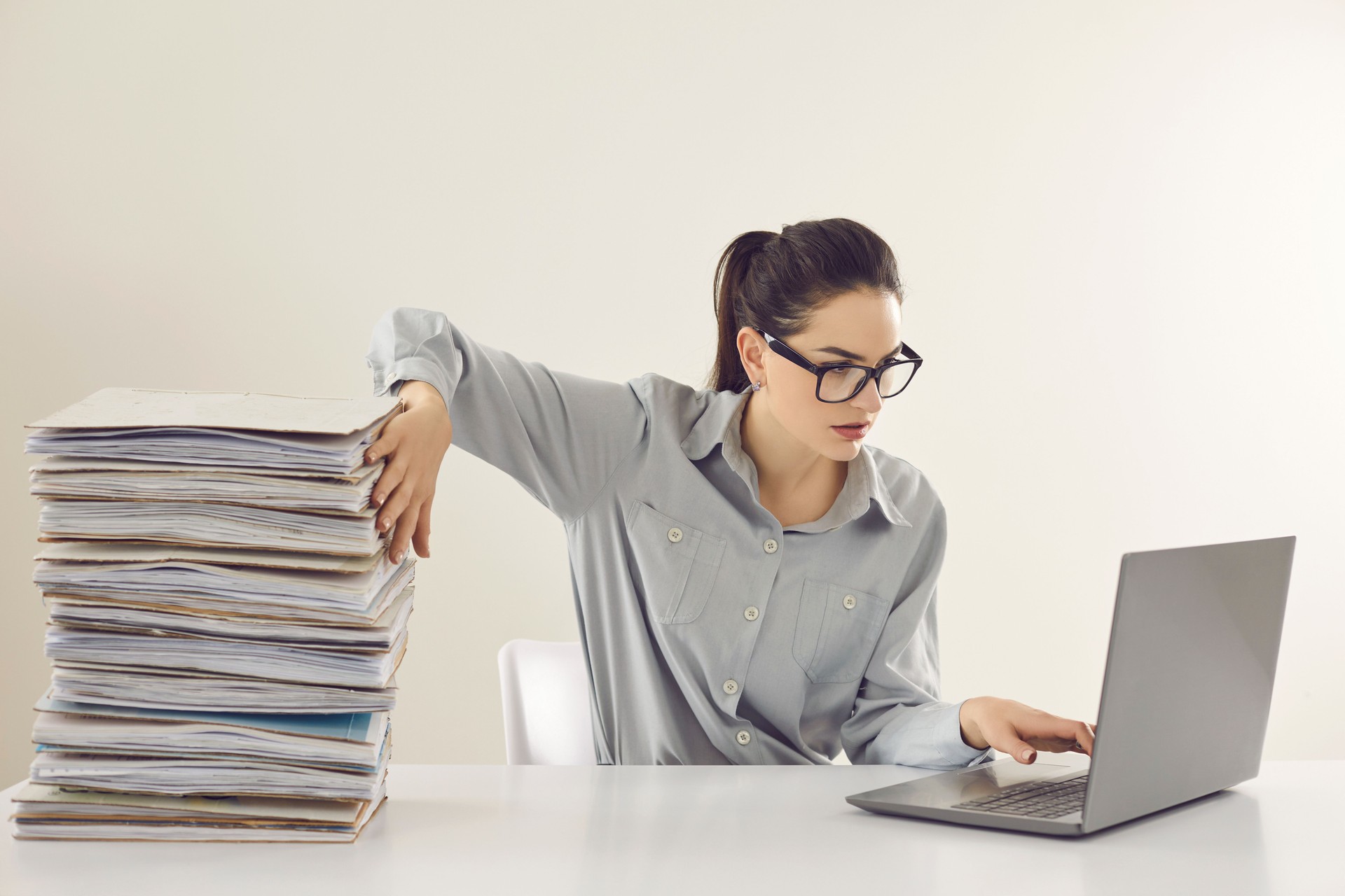 Accountant no more needs piles of papers and is working with electronic documents on laptop